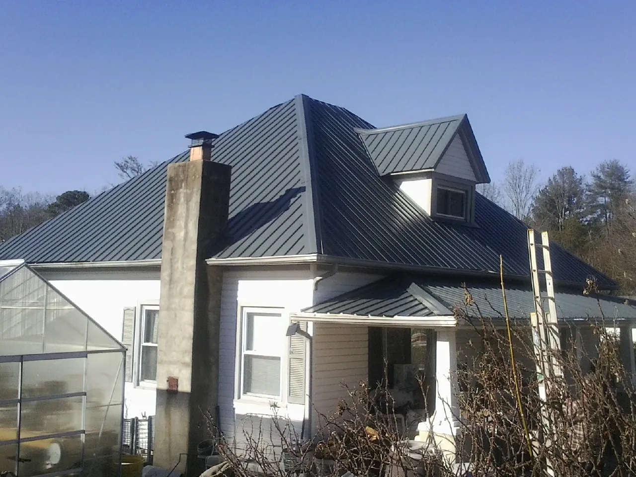 Dark blue standing seam metal roof on a white farmhouse with dormer — Slate & Tile Roof Repair by Roofing Brothers in Laurel Bloomery