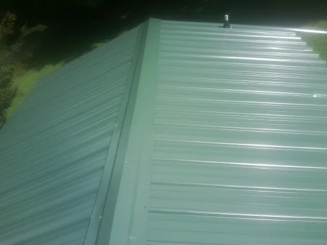 New green metal panels meeting at the ridge of a roof — Flat Roof Repair work by our crew in Laurel Bloomery