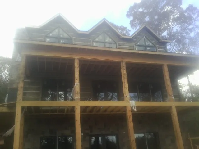Dormers and porch framing on a large log home under construction — Roof Coating work by our crew in Laurel Bloomery