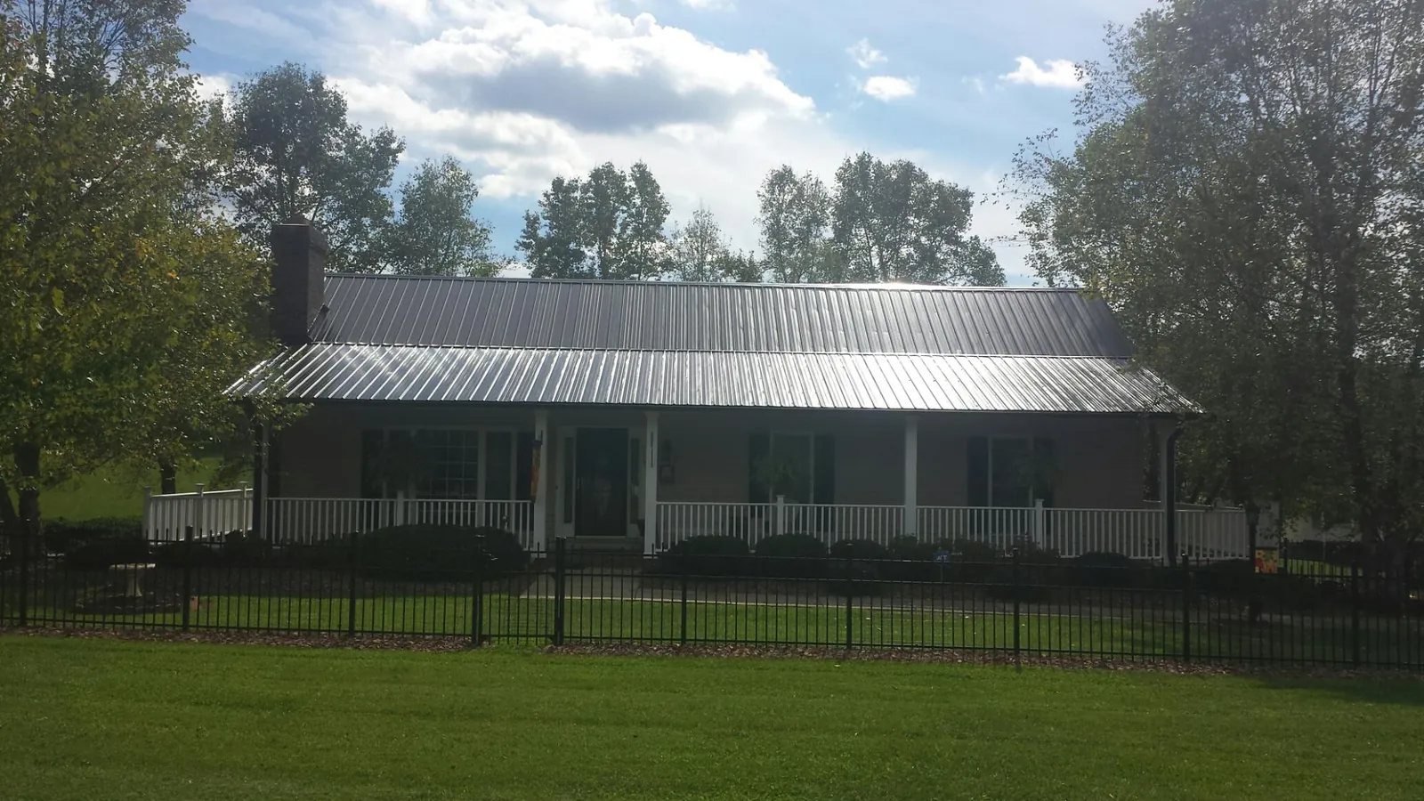 Gray metal roof on a brick ranch with a full width front porch — Gutter Guard Installation work by our crew in Laurel Bloomery