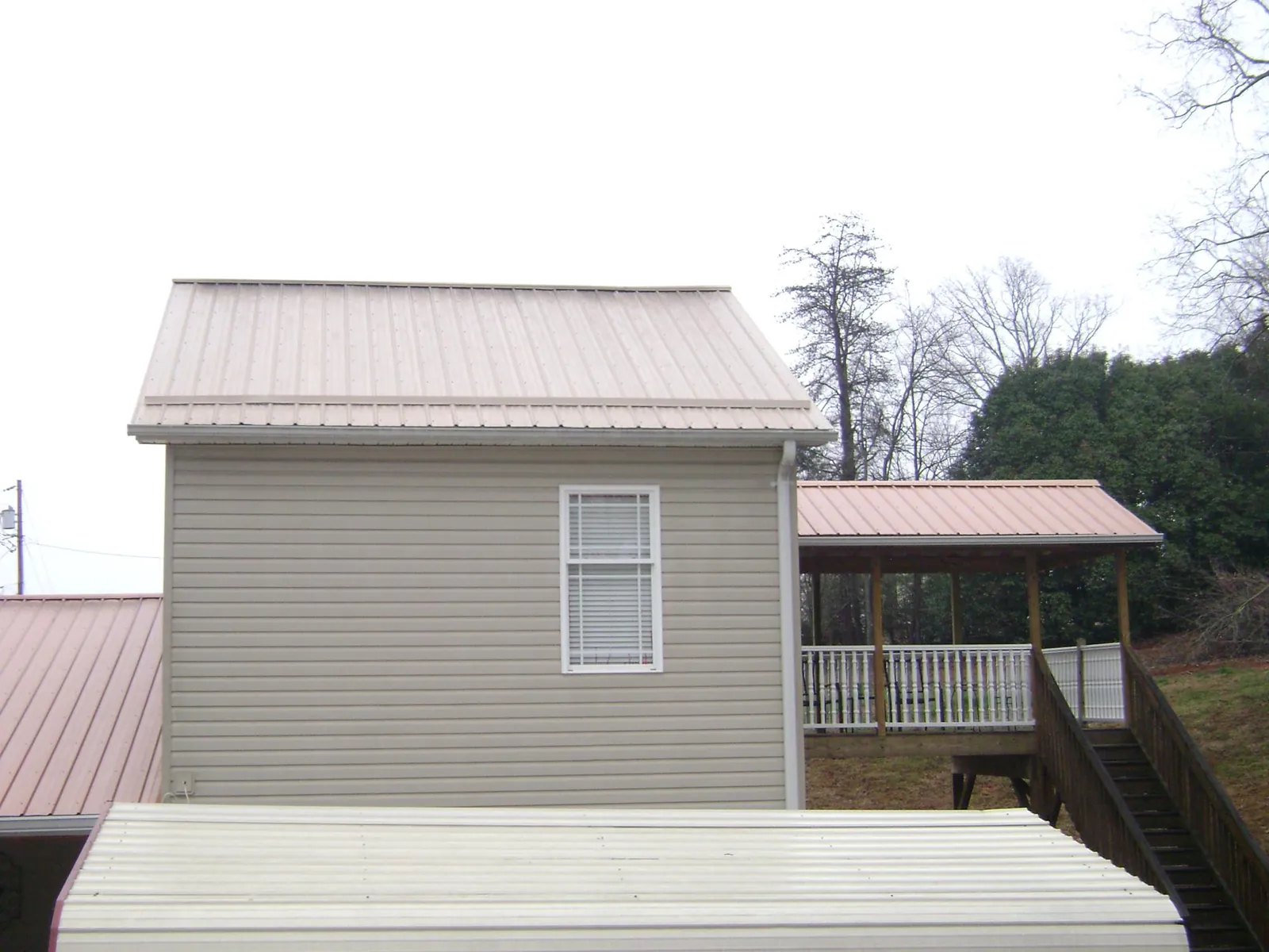Tan metal roofs on a two story addition and attached porch, from a Roof Replacement job in Laurel Bloomery