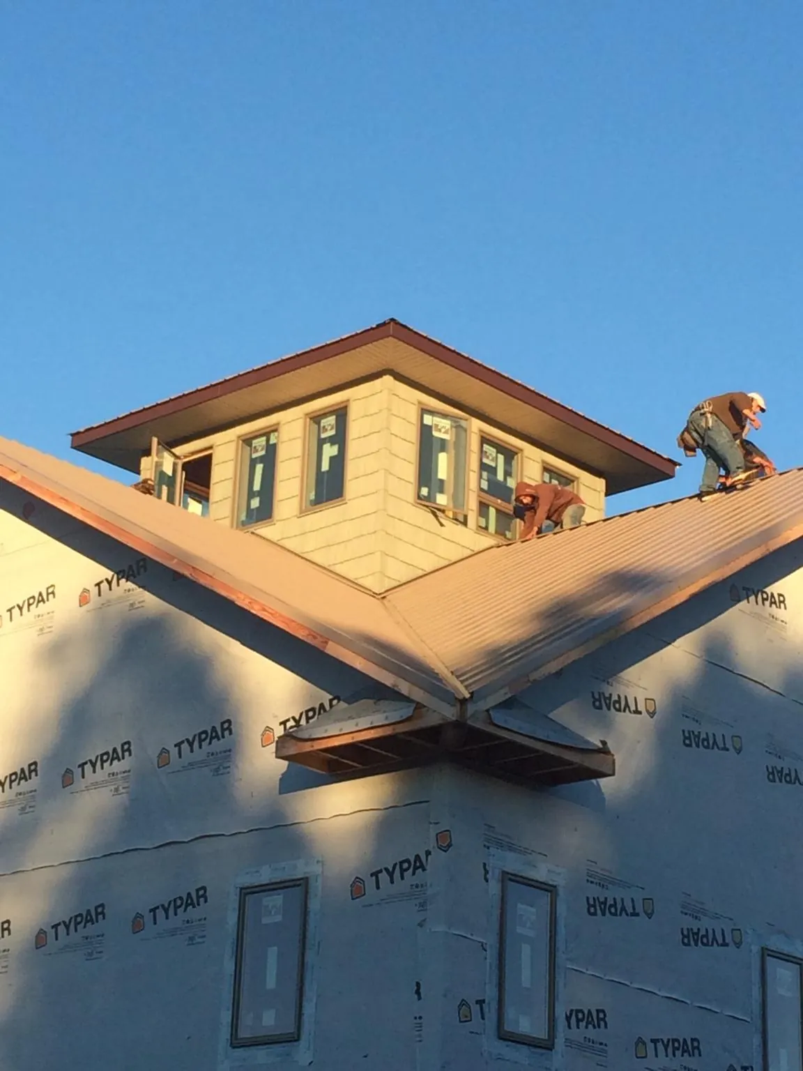 Roofers working around a rooftop cupola on a new metal roof at sunset — Roof Waterproofing in Laurel Bloomery by Roofing Brothers